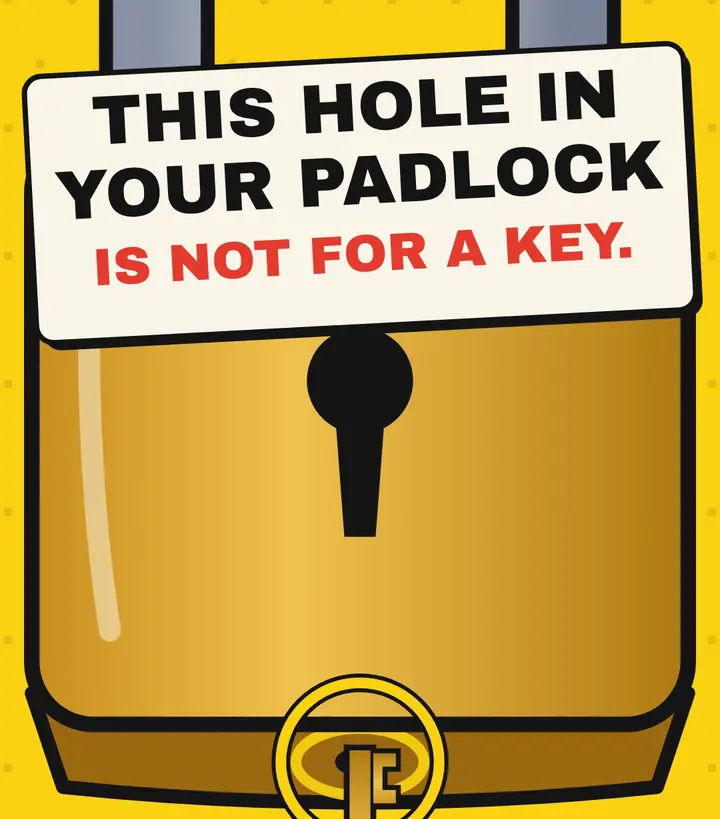Close-up of a brass padlock with a key pushed toward the small circled hole in its base, under a sign reading 'This hole in your padlock is not for a key'